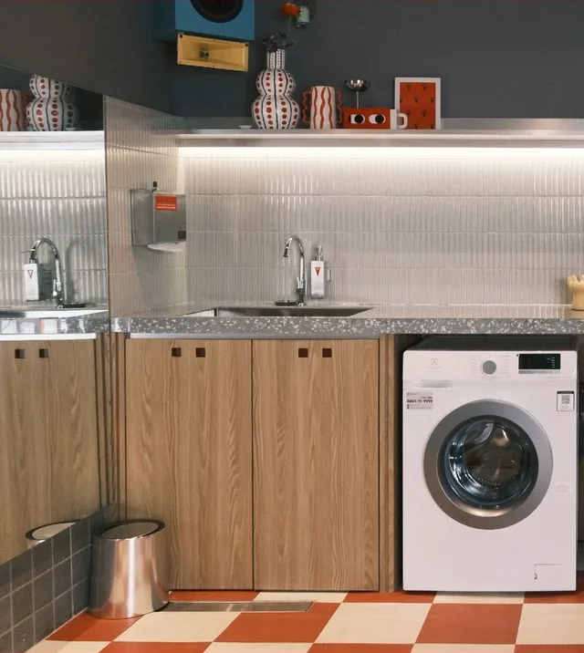 Ruang laundry self-service dengan mesin cuci dan wastafel