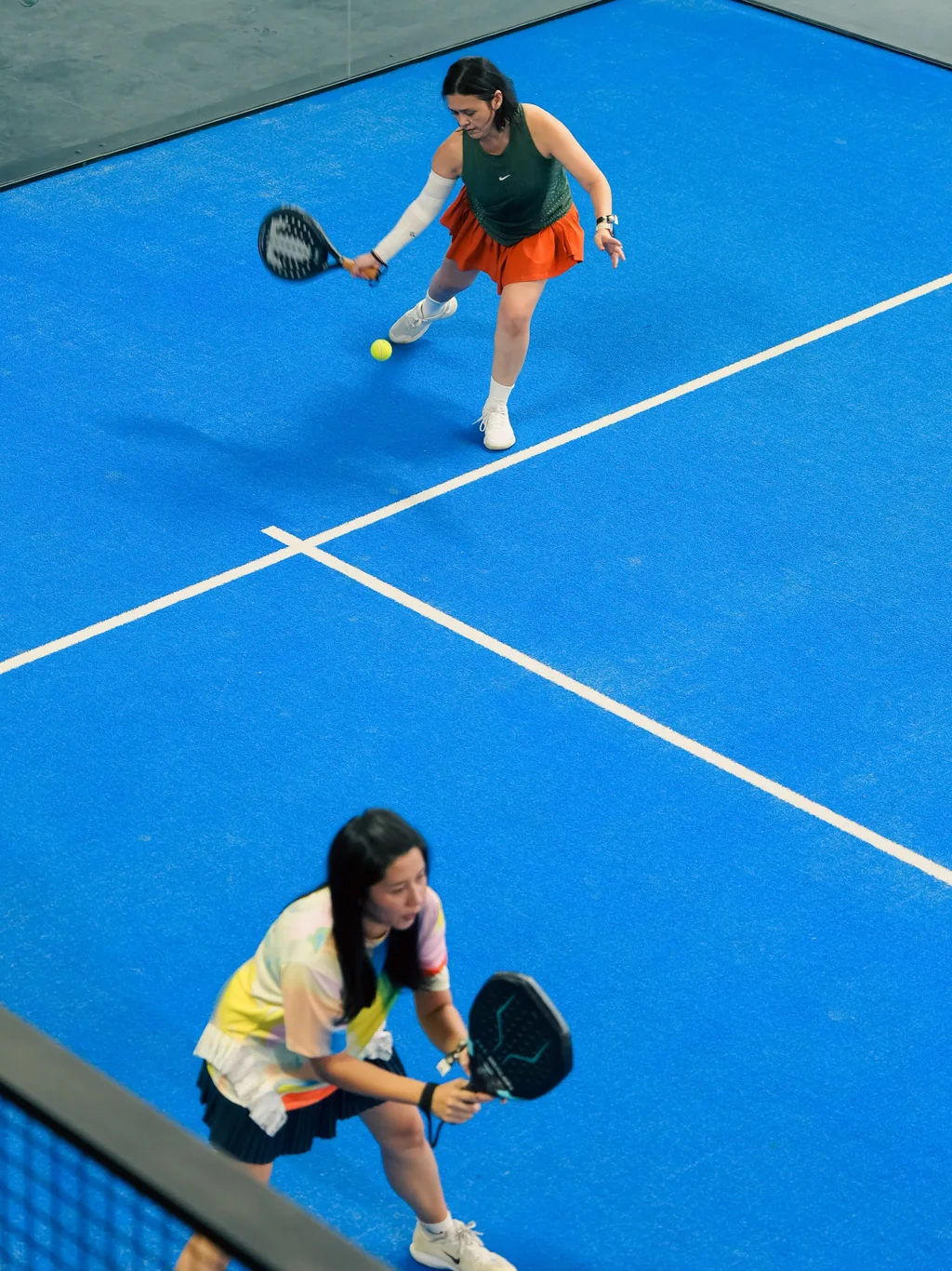 Two padel players on a blue court, seen from above