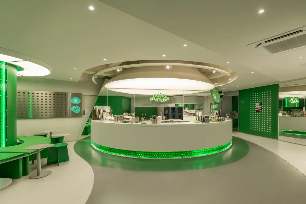Round white bar with a glowing green base under one large round light inside Noisy Matcha