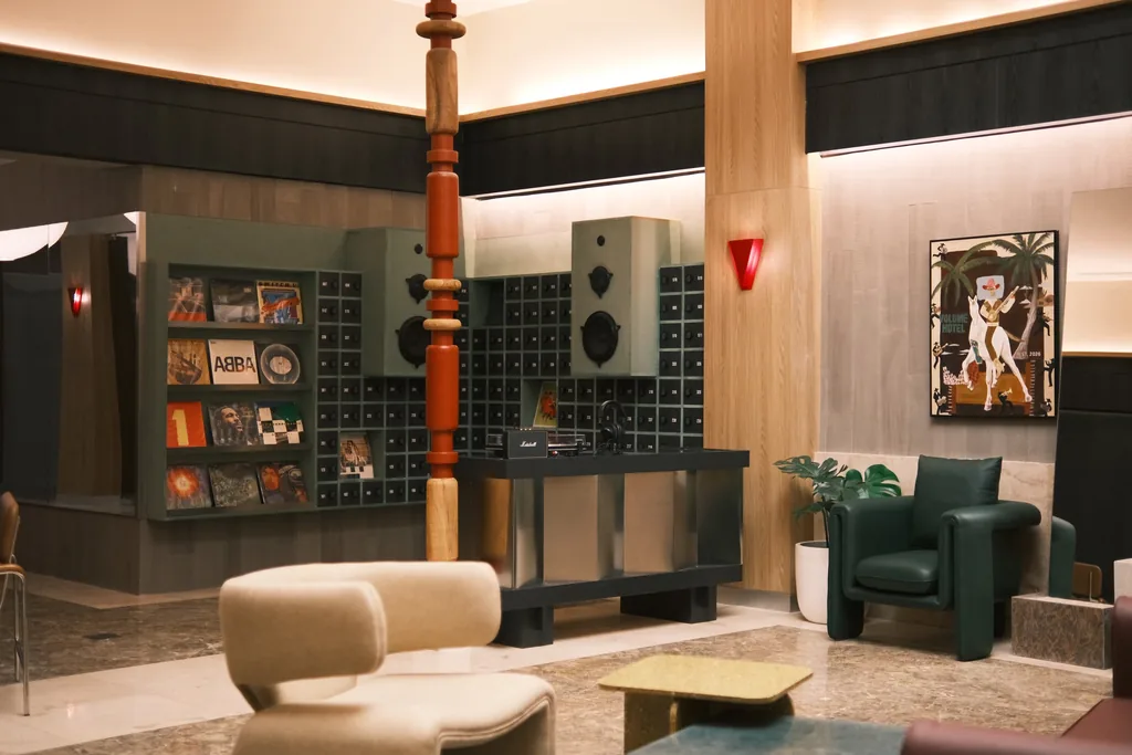 Lobi hotel dengan dinding piringan hitam, tiang ukir merah, dan kursi berlengan