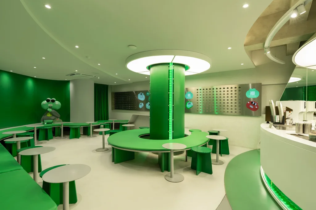 Curved green seating around a green column at Noisy Matcha, with a frog figure at the back