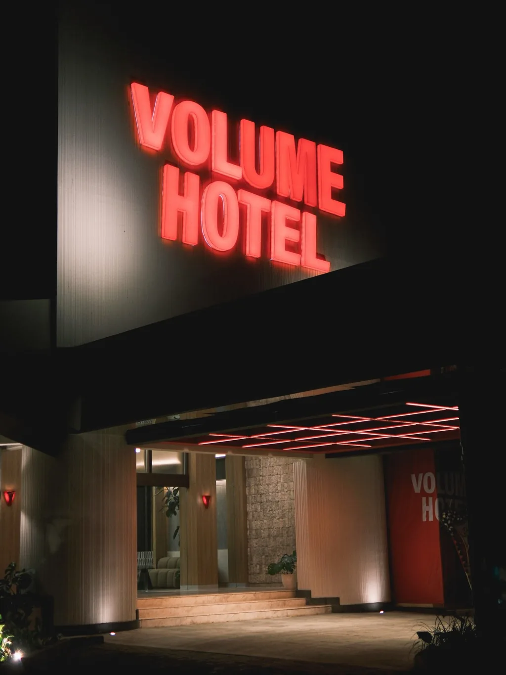Pintu masuk Volume Hotel dengan papan neon merah di malam hari